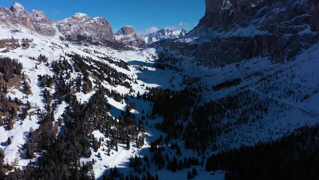 Gardena Pass and Mountains on Sunny Winter Day. South Tyrol, Dolomites, Italy. Aerial View . Drone Flies Forward, Tilt Up. Reveal Shot