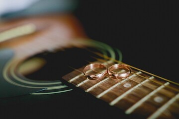 Wedding rings lie on the strings of a guitar