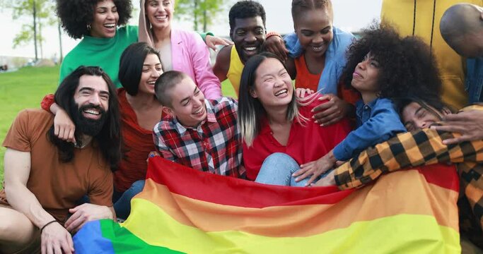 Diverse people having fun holding LGBT rainbow flag outdoor 