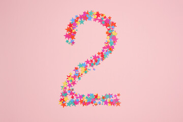 Number 2 or two made from decorative multi-colored stars. Holiday numbers or figures. Top view