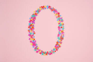 Number 0 or zero made from decorative multi-colored stars. Holiday numbers or figures. Top view