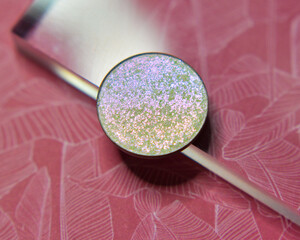 Single glittery white eye shadow on pink floral background with acrylic