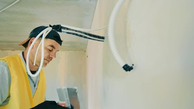 Repair work in the room. Plasterer painter construction worker plasters the wall with a plaster spatula. Plastering and leveling of unevenness on a wall by means of finishing plaster.