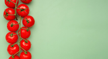 Red ripe fresh cherry tomatoes over a green background