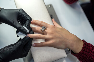 manicurist makes the client preparatory procedures for applying varnish in a beauty salon