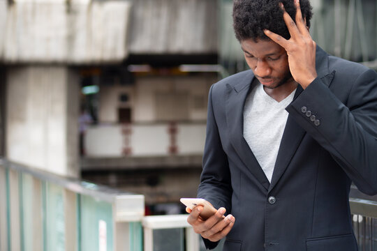 upset African businessman or office worker having problem using smartphone app