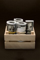 A lot of dollars in a wooden box black background tied with an elastic band.