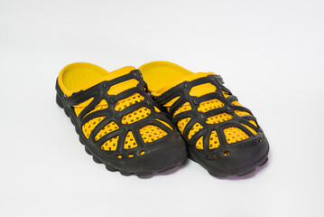 A pair of men's rubber black and yellow slippers isolated on a white background.