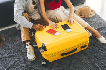 Young adult southeast asian couple hand place on luggage with passport for getting ready for holidays travel - obrazy, fototapety, plakaty