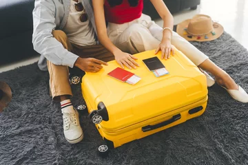 Tuinposter Young adult southeast asian couple hand place on luggage with passport for getting ready for holidays travel © dodotone