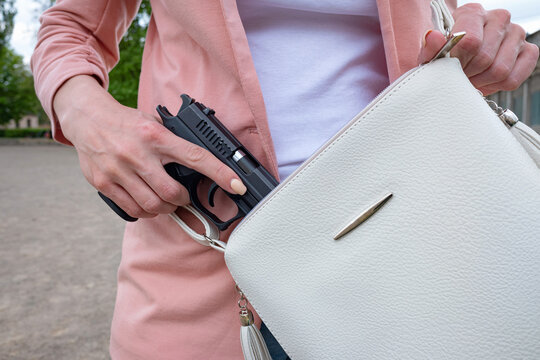 A woman pulls a semi-automatic 9mm pistol from her bag.Legal firearms to protect yourself from robbery, rape.