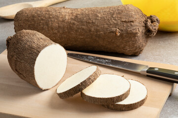  Whole and sliced raw African yam on a cutting board close up - obrazy, fototapety, plakaty
