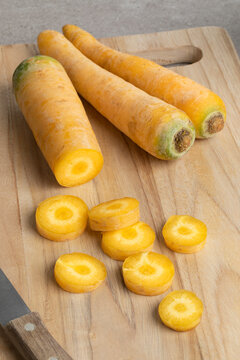 Fresh raw yellow carrots and slices on a cutting board