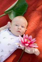 A cute little newborn baby lying on the red blanket,vertical portrait