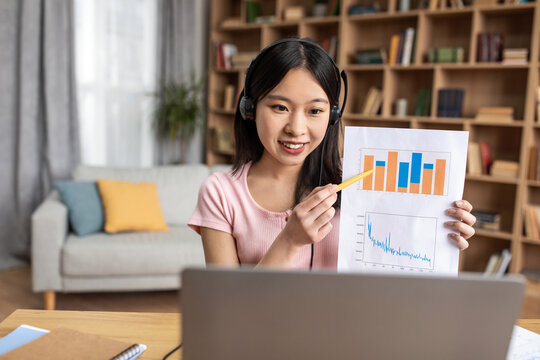 Young Korean Financial Analyst Having Video Call On Laptop, Giving Virtual Presentation And Showing Statistics To Webcam