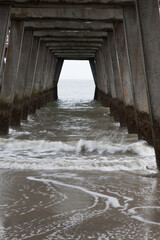 Ocean waves under a wooden fishing pier