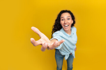 Excited young woman outstretching hand, trying to reach something - obrazy, fototapety, plakaty