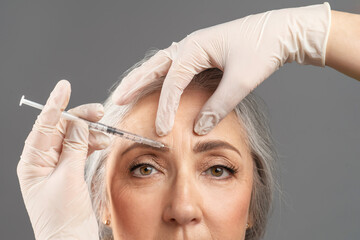 Mature skin rejuvenation. Closeup portrait of senior woman receiving cosmetic treatment with beauty injection