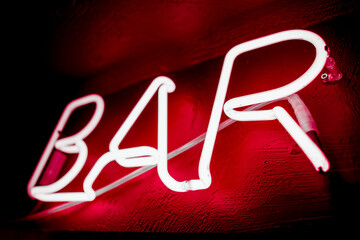 Neon inscription BAR on the wall. Neon inscription BAR in different colors. Multicolored neon inscription BAR on dark background