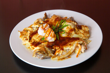 Prawn shrimp chicken pan fried omelette of traditional Cantonese yum-cha Asian gourmet cuisine meal food dish on the white serving plate and brown red table
