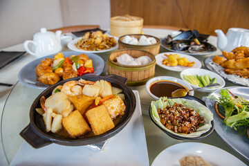 Food platter combo set of traditional Cantonese yum-cha dim sum Asian gourmet cuisine meal food dish on the round table includes dishes of duck, pork, fish, chicken, vegetables, tea, dumplings, buns