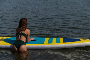 Beautiful caucasian woman is swimming on a SUP board.