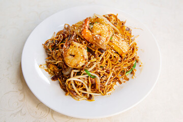 Singapore stir-fried noodles with prawn of traditional Cantonese yum-cha Asian gourmet cuisine meal food dish on the white serving plate and white table
