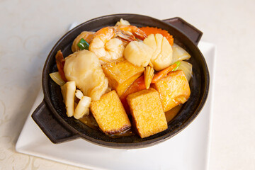 Claypot seafood tofu and vegetable of traditional Cantonese yum-cha Asian gourmet cuisine meal food dish on the white serving plate and white table