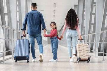 Fototapeta na wymiar Cute little girl walking with parents together in airport terminal