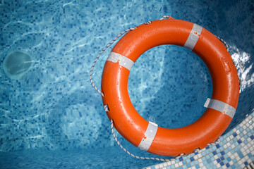 orange life buoy in the pool. orange lifebuoy on a background of water. Life buoy, for the...