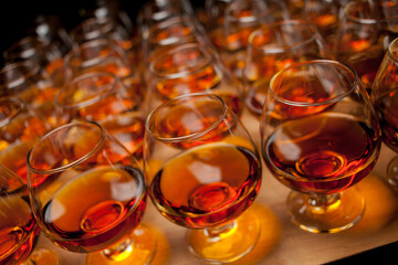 glasses with cognac, whiskey stand on the bar. a lot of glasses with cognac. alcohol in the...