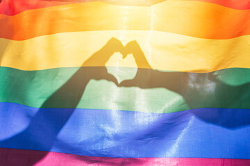 LGBTQ rainbow colors flag, a symbol for the homosexual community, two hands making a heart shape...