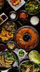 Top view of Korean Grilled BBQ combo sets on the traditional grill table, kimchi soup, fried dumplings, pancake, fried chicken, pickle dishes
