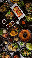 Top view of Korean Grilled BBQ combo sets on the traditional grill table, omelette, bibimbap, pancake, fried chicken, pickle dishes, fried dumplings