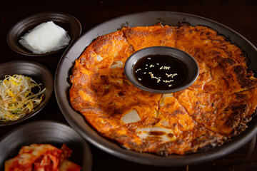 Korean Grilled BBQ combo sets with kimchi pancake with pancake sauce on the dark plate and black table vibe background