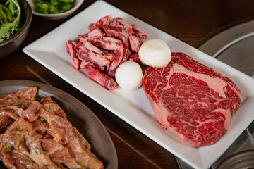 Korean Grilled BBQ combo with wagyu beef set on the traditional grill table, with mushroom and pickle dishes