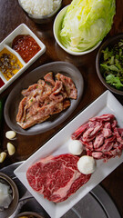 Top view of Korean Grilled BBQ combo with wagyu beef set on the traditional grill table, with lettuce, dipping sauce and pickle dishes