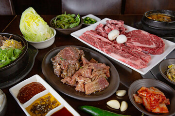Korean Grilled BBQ combo with wagyu and marinated beef set on the traditional grill table, with lettuce, dipping sauce, rice and pickle dishes