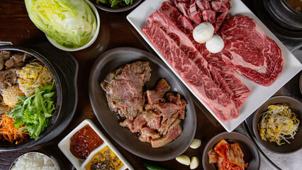 Top view Korean Grilled BBQ combo with wagyu and marinated beef set on the traditional grill table, with lettuce, dipping sauce, rice and pickle dishes