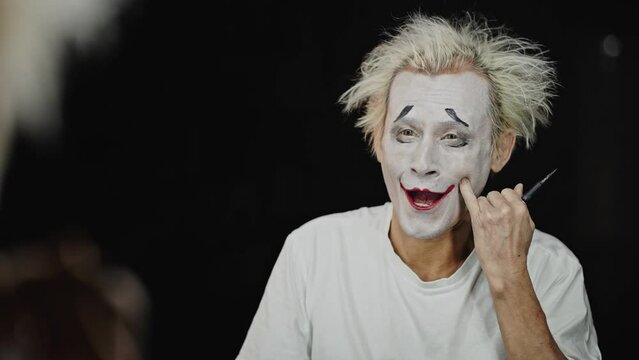 Experienced mime looks at mirror reflection showing grimaces