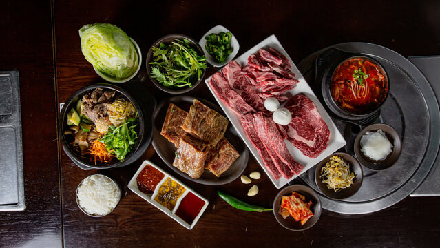 Top view Korean Grilled BBQ combo with marinated beef meat set on the traditional grill table, with bibimbap, soup, dipping sauce and pickle dishes