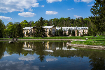 Fototapeta na wymiar Spa park in Nałęczów on sunny day, blue sky, reflections in the water
