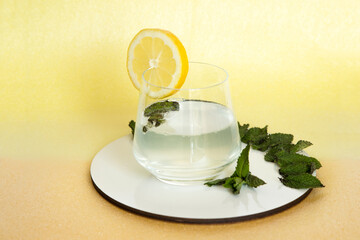 Refreshing and energizing drink made with lemon and mint placed on a yellow-orange background.