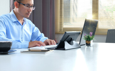 Businessman works on his computer. In the office, a young professional is utilizing a laptop and a smartphone. Management, finance.