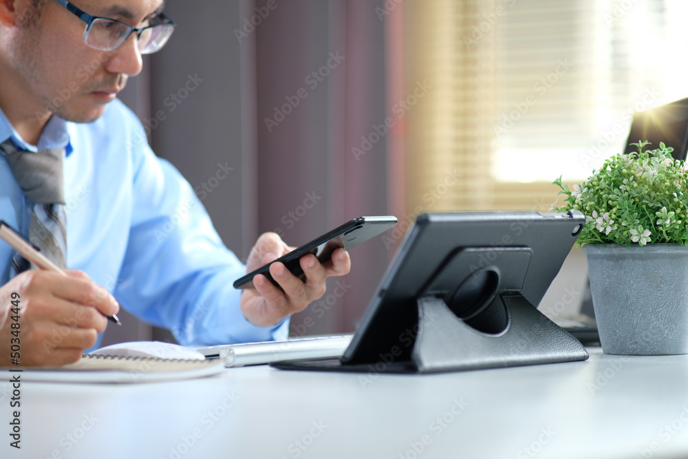 Poster man works by typing on a computer while texting on his cell phone. online learning education for stu