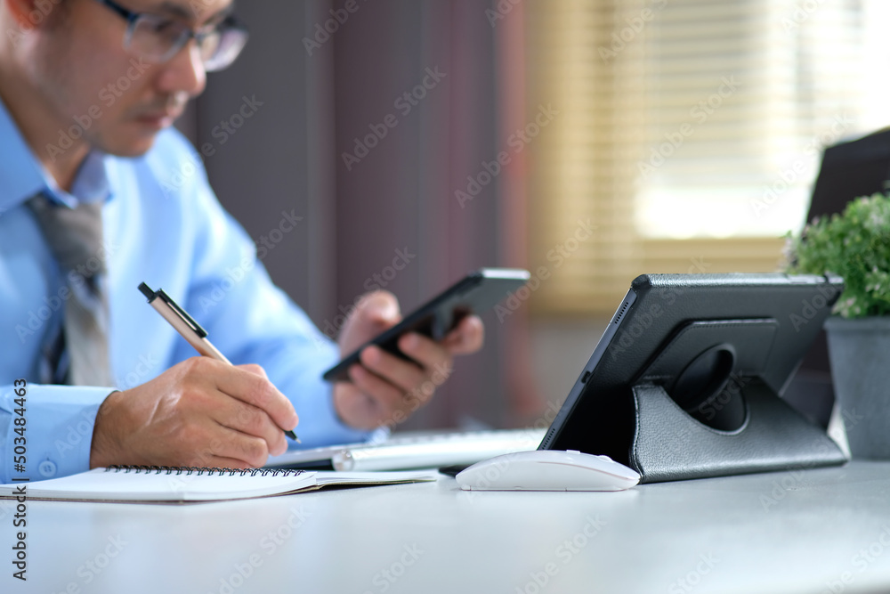 Poster man works by typing on a computer while texting on his cell phone. online learning education for stu