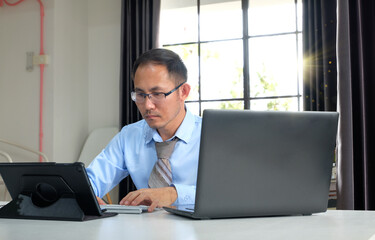 Man using a laptop computer and phone at work in a office, online study, internet marketing, working from home, office workspace freelance concept