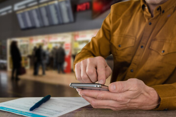 Man with modern smartphone filling travel insurance claim form in airport