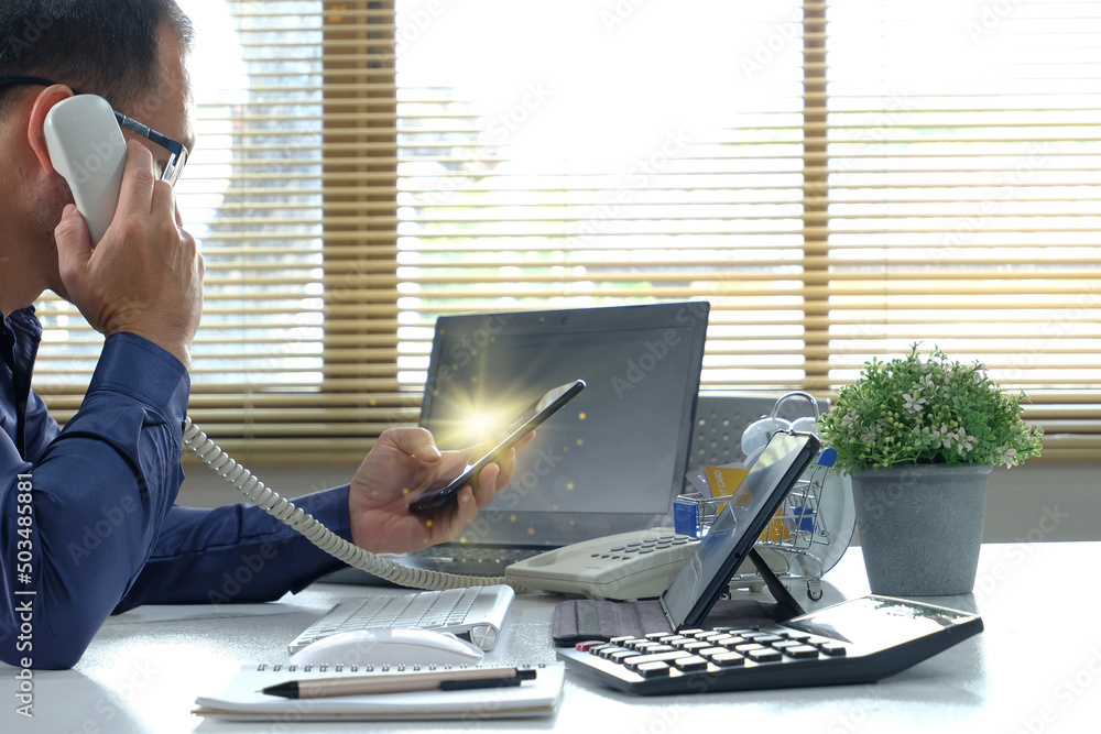 Poster man works by typing on a computer while texting on his cell phone. online learning education for stu