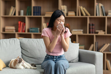 Pet allergy concept. Young korean lady sneezing and holding paper tissue, suffering from runny nose...
